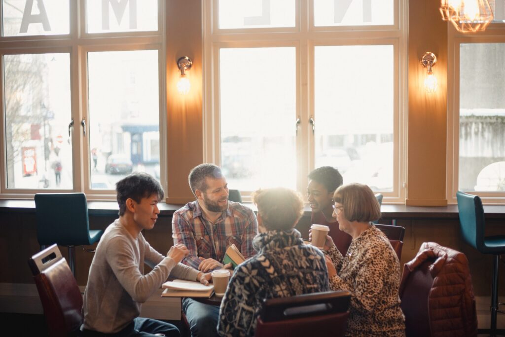 Small group of people with a mixed age range sitting around a table in a cafe