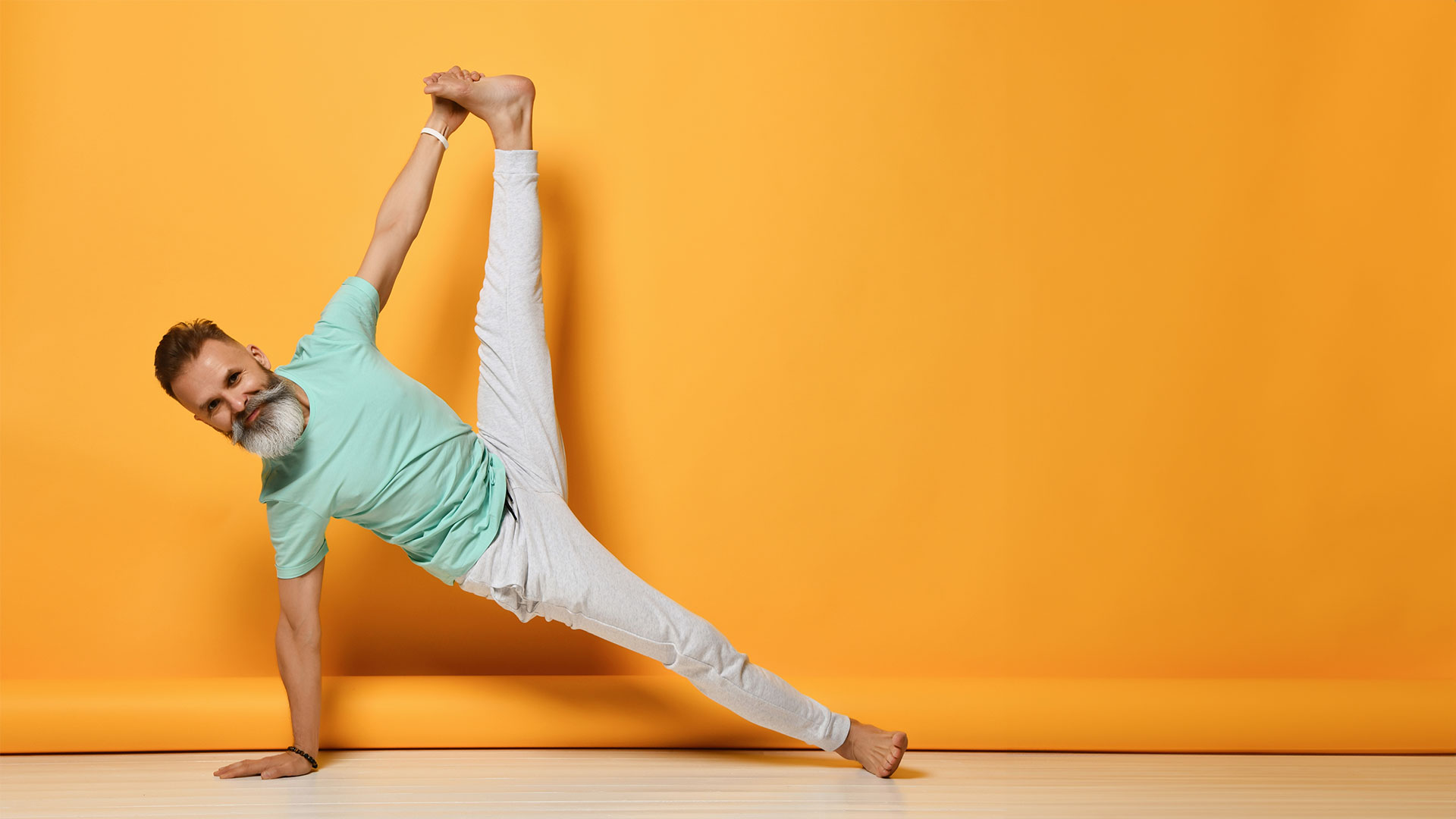 Un homme faisant du yoga étend à nouveau un mur jaune vif