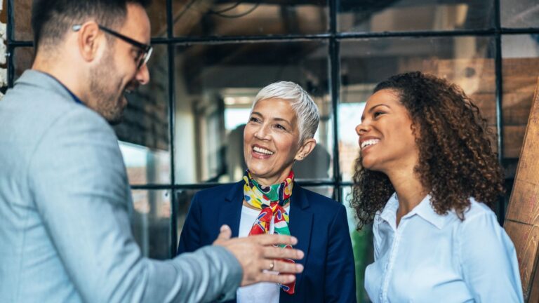 Three business professionals engaged in a discussion, exchanging ideas in a collaborative office environment.