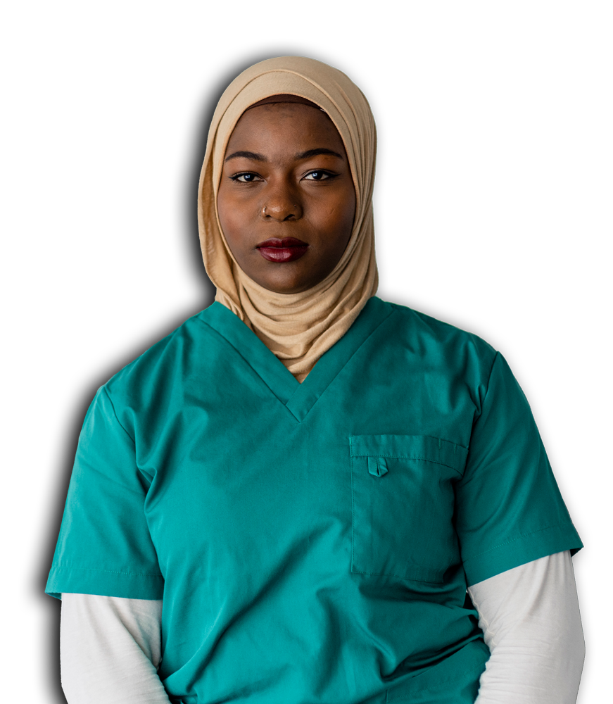 A woman in a green scrub suit is seated, appearing relaxed and focused in her environment.